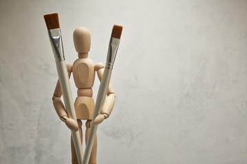 Wooden mannequin with paintbrush