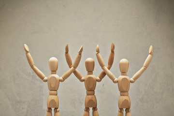 Three wooden mannequin hands up as winners