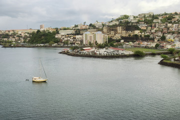 Naklejka premium Small yellow boat and many colorful buildings on the coast of Martinique