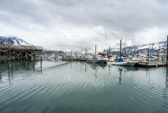 View of fishing boats moored at the port of Seward and snow covered mountains, Alaska