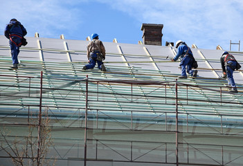 Roofers are working on the roof of a building