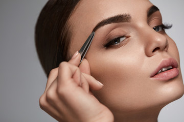 Fototapeta premium Beautiful Woman Plucking Eyebrows. Beauty Brows Correction