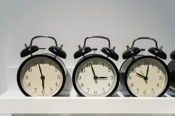 close up face of many Black alarm clock on white shelf