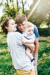 Fototapeta premium Young family, mother father and baby son happy posing in park