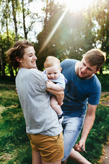 Fototapeta premium Young family, mother father and baby son happy posing in park