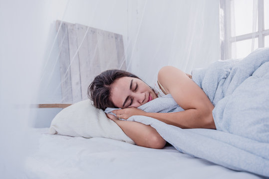 Woman Sleeping In A Bed Under A Mosquito Net.