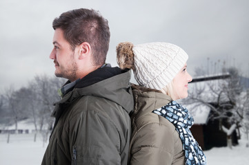 Young happy couple standing back to back