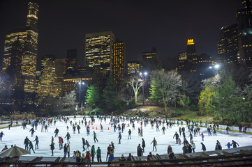 Skaters take advantage of a mild night at an ice skating rink in Central Park against the Midtown,...