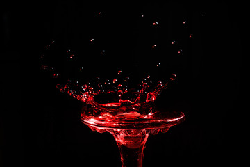 Close-up a drop of wine in the form of a crown is split on the glass  isolated on a black...