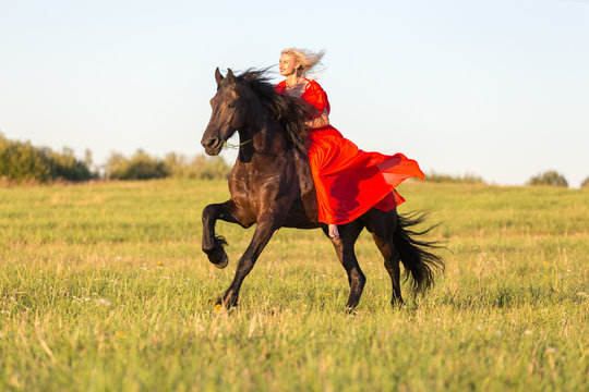 Beautiful lady in red riding black horse.