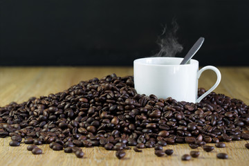 Cup of coffee in pile of seeds of coffee on brown plate / Blurred and Select focus image, 