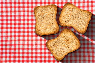 Healthy rusks of wholemeal flour on a table with checkered tablecloth