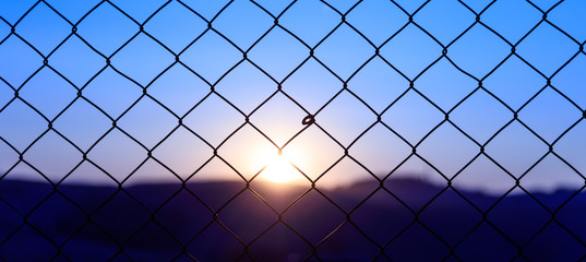 Wire mesh fence on a sunset background