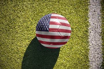 Obraz premium football ball with the national flag of united states of america lies on the field