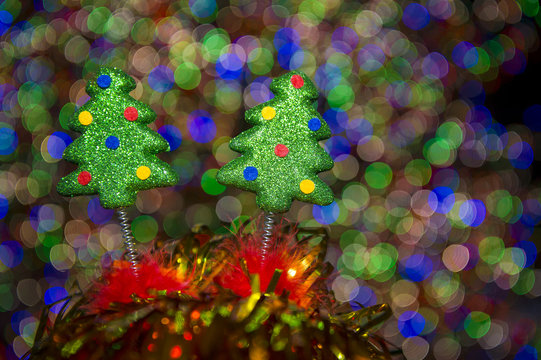 Decorative springy Christmas trees on novelty headwear standing against colorful bokeh light bubbles 