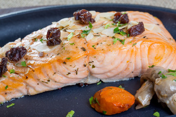 close up with grilled salmon and boiled mushrooms on a black pla
