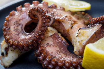 Close up squid tentacles with lemon on black plate