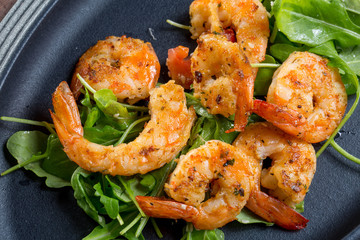 close up with fresh fried shirmps with arugula on a black plate