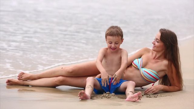Young Mother and Her Son Playing in the Sand, on the Coast
