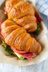 croissants with argugula, jamon, cheese and tomato on wooden sur