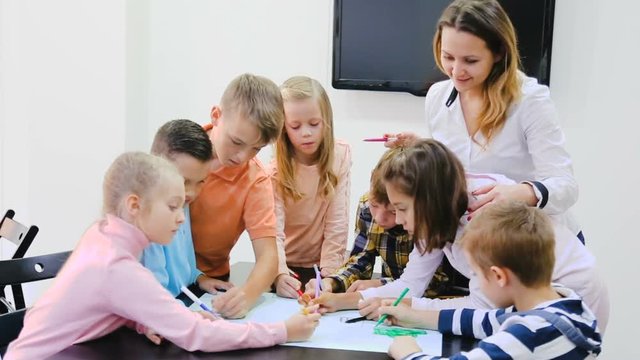 Professor and elementary age children drawing together one picture 