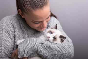 Young woman holding kitten isolated on grey.