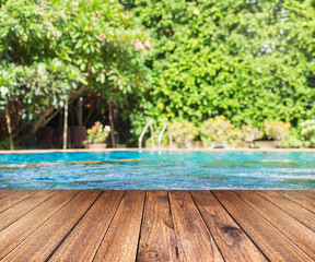 Wooden plank floor against swimming pool with green trees