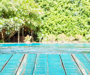 Wooden plank floor against swimming pool with green trees