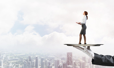Attractive businesswoman on metal tray with red book in hands against cityscape background