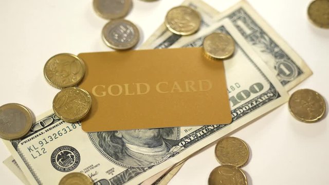 Euro coins falling on the gold card and dollars. - Powered by Adobe