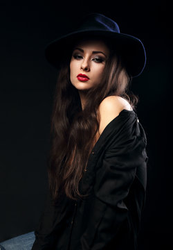 Expressive female model posing in black shirt and elegant hat wi
