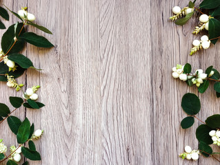 Frame of green branches of ghostberry on wooden table. Top view, flat lay