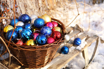Fototapeta na wymiar Christmas decorations in a wicker basket on a wooden sled. Winter Garden.