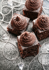 Brownie cake bites with chocolate cream and berries - dessert idea for holiday party on dark Christmas background, blank space for recipe text