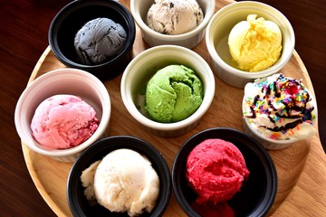 Top view of table colorful ice cream in small cup placed on tray brown wood.