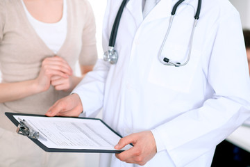 Close up of a male doctor holding an application form while consulting patient