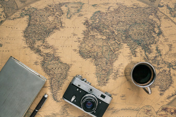 Vintage Camera, Notebook, Pen, Metal Coffee Cup on Retro World Map