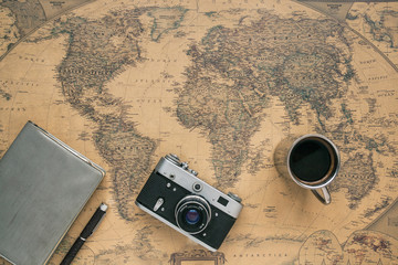 Vintage Camera, Notebook, Pen, Metal Coffee Cup on Retro World Map