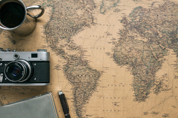 Vintage Camera, Notebook, Pen, Metal Coffee Cup on Retro World Map