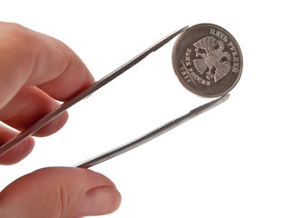 The hand holding the tweezers coin of five rubles