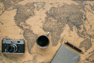 Vintage Camera, Notebook, Pen, Metal Coffee Cup on Retro World Map