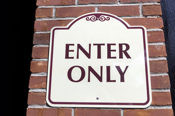 ENTER ONLY sign attached to brick wall.