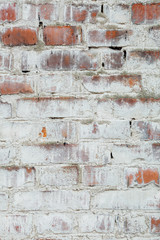 Poorly painted wall of damaged red brick with white paint, textu