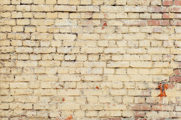 Poorly painted wall of damaged red brick with yellow paint, text