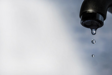 last drops of water from tap isolated on blue background