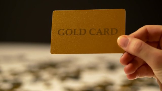 Woman's hand replaces the piggy bank on gold plastic card