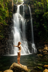 Young woman in bikini standing by Middle Tavoro Waterfalls in Bo