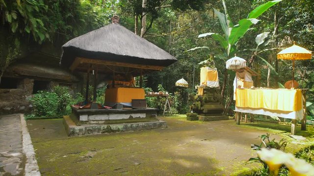 Holy temple in the forest on Bali island. Stone chancel inside tropical garden with traditional features of indonesian culture. Sacred spirit house is protecting people from evil and demons.