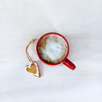 warm how love/ red mug with a frothy coffee and ginger cookies on a light table top view 