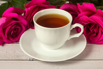 Romantic St Valentine's setting with tea cup and red roses